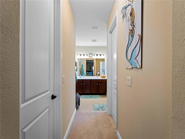 corridor featuring light carpet and a textured ceiling