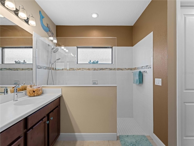 bathroom featuring tile patterned flooring, vanity, and tiled shower