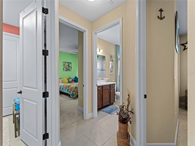 hall featuring light tile patterned floors and a textured ceiling