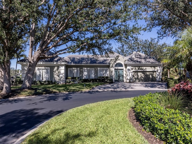 ranch-style home with a garage and a front lawn