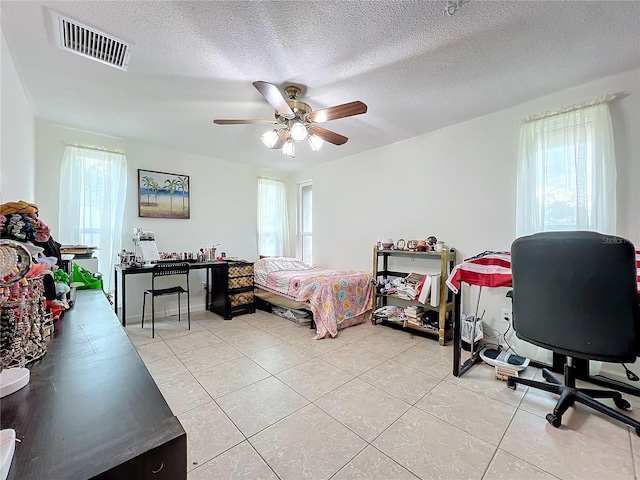 bedroom with ceiling fan, multiple windows, light tile patterned floors, and a textured ceiling