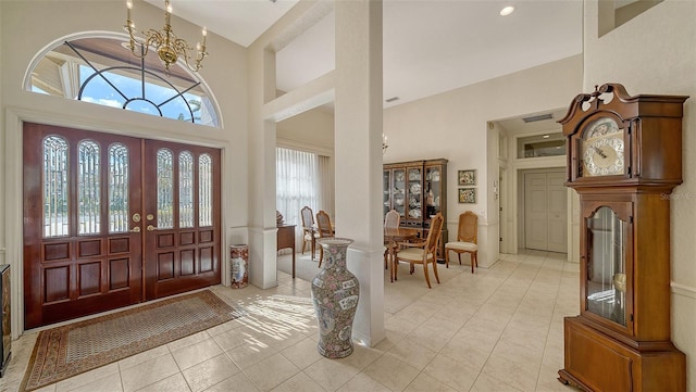 tiled entryway with a towering ceiling, a wealth of natural light, and a chandelier