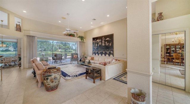 living room with a towering ceiling, ceiling fan with notable chandelier, and light tile patterned floors