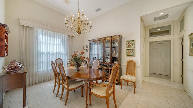 tiled dining room featuring an inviting chandelier and a high ceiling