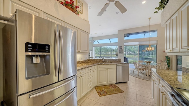 kitchen featuring sink, stone countertops, light tile patterned floors, appliances with stainless steel finishes, and pendant lighting