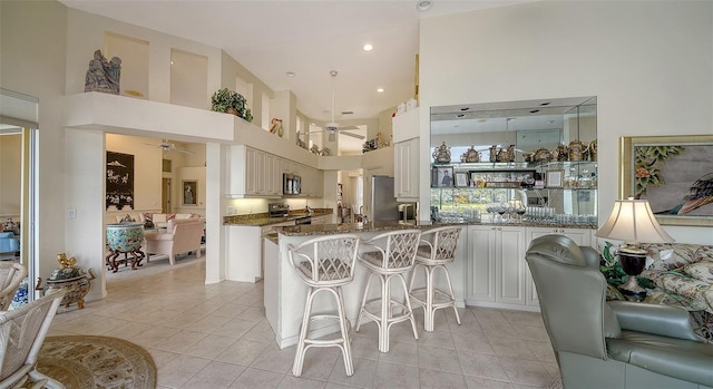 kitchen with white cabinets, dark stone counters, ceiling fan, kitchen peninsula, and stainless steel appliances