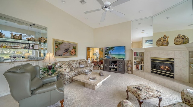 carpeted living room featuring ceiling fan, lofted ceiling, and a tiled fireplace