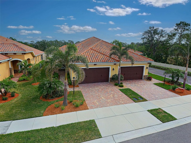 mediterranean / spanish-style home featuring a garage and a front lawn