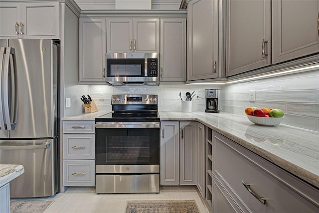 kitchen with backsplash, stainless steel appliances, light stone countertops, and gray cabinetry