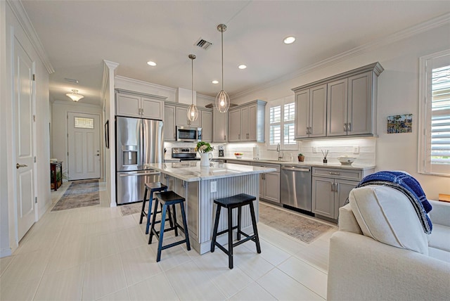 kitchen featuring a breakfast bar, decorative light fixtures, ornamental molding, appliances with stainless steel finishes, and a kitchen island