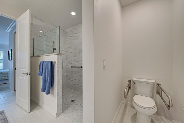 bathroom with tiled shower, toilet, and tile patterned flooring