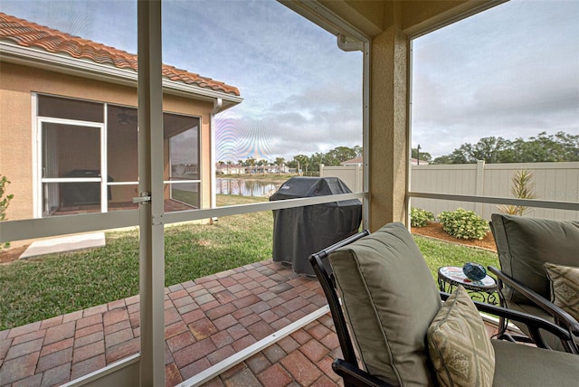 view of patio / terrace featuring grilling area, a sunroom, and a water view