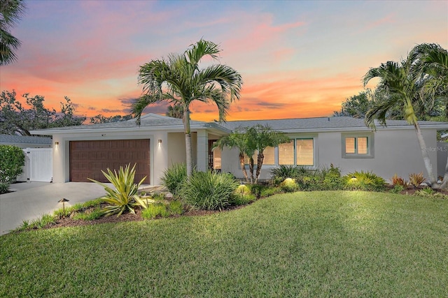 single story home featuring a garage and a lawn