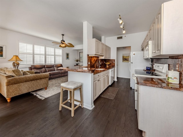 kitchen with white appliances, a kitchen bar, white cabinets, and tasteful backsplash