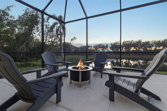 view of patio / terrace with a lanai, an outdoor fire pit, and a water view