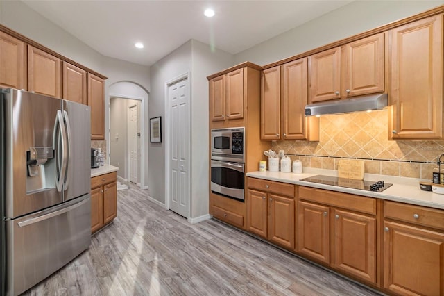 kitchen featuring appliances with stainless steel finishes, light countertops, under cabinet range hood, and decorative backsplash