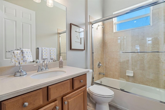 full bath with combined bath / shower with glass door, vanity, and toilet