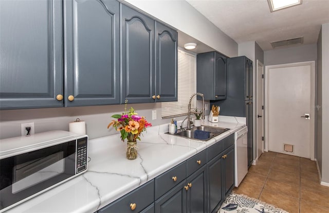 kitchen with sink, light tile patterned floors, blue cabinetry, white dishwasher, and light stone counters