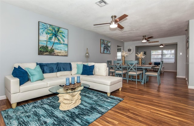 living room featuring ceiling fan, dark hardwood / wood-style flooring, and a textured ceiling