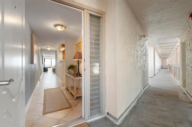 hall with light tile patterned flooring and a textured ceiling