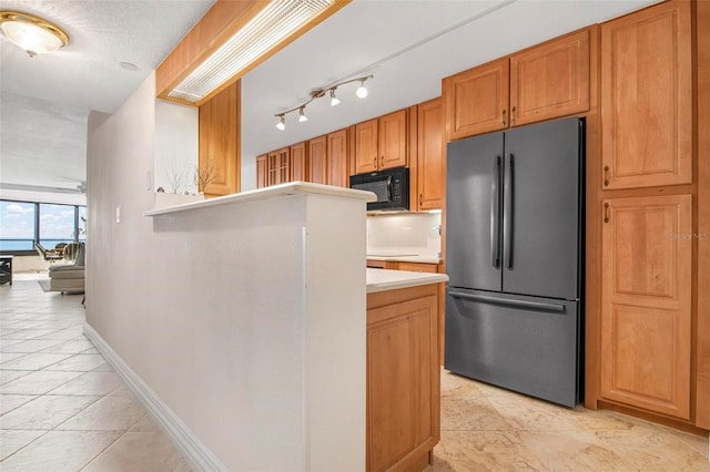 kitchen featuring light tile patterned floors, a textured ceiling, and refrigerator