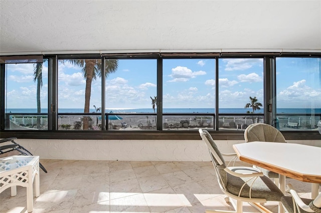 sunroom / solarium featuring a water view and a view of the beach