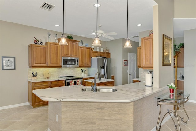 kitchen featuring appliances with stainless steel finishes, tasteful backsplash, decorative light fixtures, light stone countertops, and sink