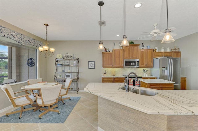 kitchen featuring appliances with stainless steel finishes, tasteful backsplash, a kitchen island with sink, hanging light fixtures, and sink