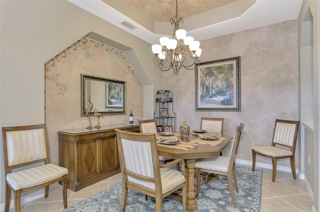 tiled dining room with a raised ceiling and a notable chandelier