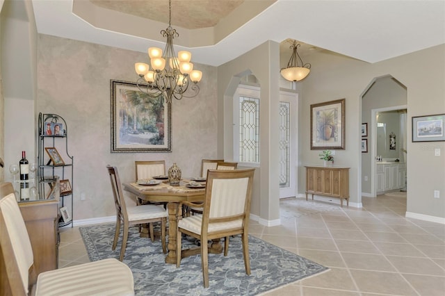 dining area featuring light tile patterned flooring, a tray ceiling, and a notable chandelier