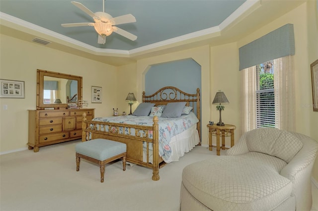 carpeted bedroom with ceiling fan, ornamental molding, and a raised ceiling