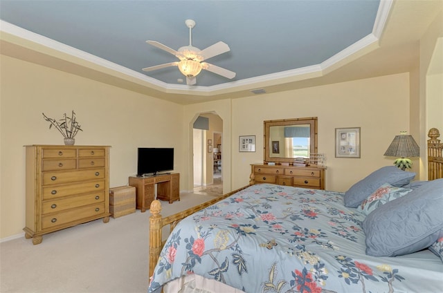 bedroom with ceiling fan, light colored carpet, a tray ceiling, and ornamental molding