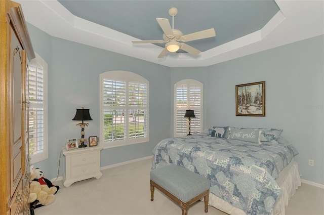 carpeted bedroom with ceiling fan and a raised ceiling