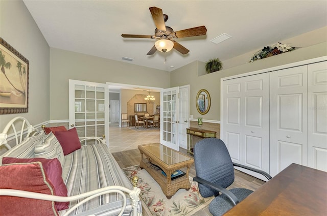 home office with ceiling fan with notable chandelier, french doors, and light wood-type flooring