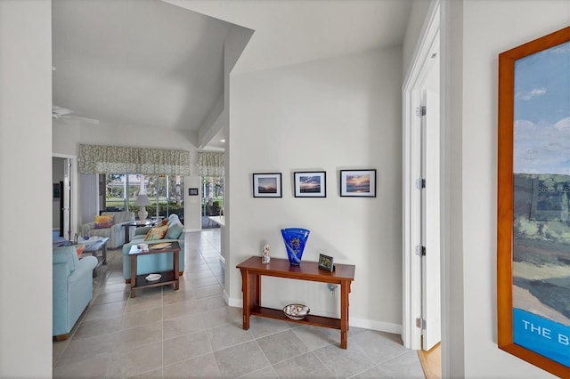 corridor with light tile patterned floors and lofted ceiling