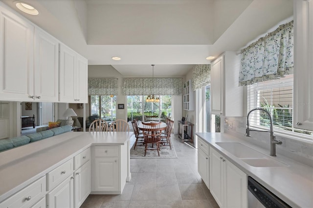 kitchen with white cabinets, dishwasher, decorative light fixtures, sink, and kitchen peninsula