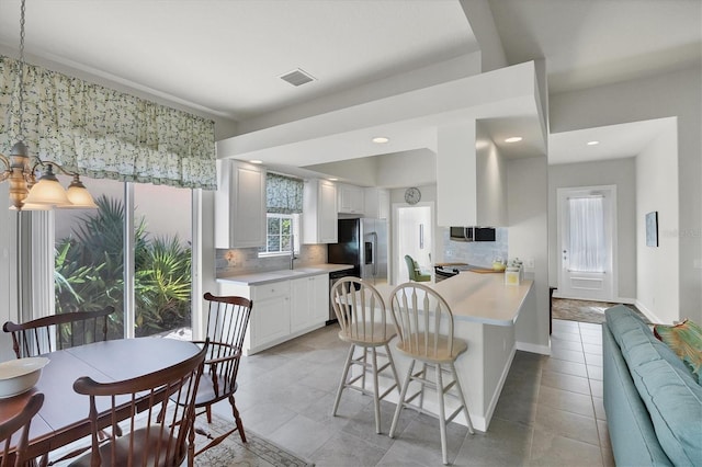 kitchen with white cabinetry, appliances with stainless steel finishes, tasteful backsplash, and a breakfast bar