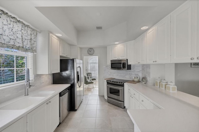 kitchen with tasteful backsplash, light tile patterned floors, white cabinets, sink, and stainless steel appliances