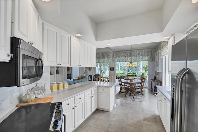 kitchen with kitchen peninsula, pendant lighting, appliances with stainless steel finishes, white cabinets, and light tile patterned flooring