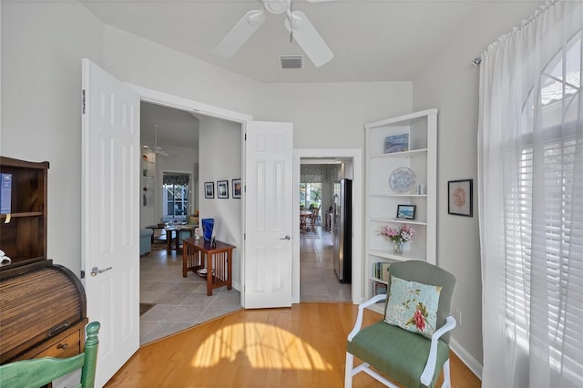 sitting room with ceiling fan and wood-type flooring