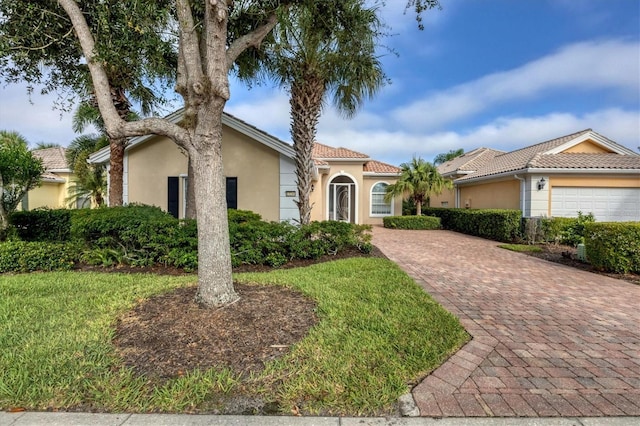 mediterranean / spanish house with a garage and a front lawn