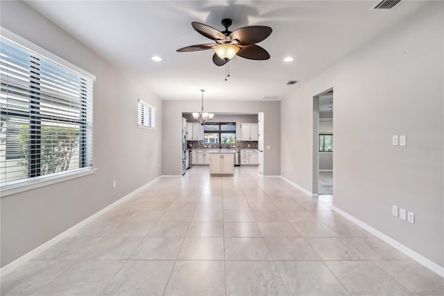 unfurnished living room featuring ceiling fan with notable chandelier and light tile patterned floors