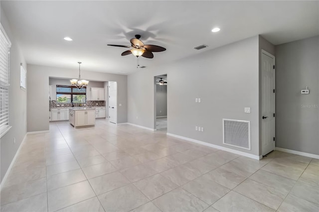 unfurnished living room with ceiling fan with notable chandelier