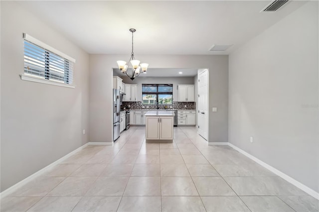 kitchen with a kitchen island, pendant lighting, tasteful backsplash, stainless steel appliances, and a healthy amount of sunlight