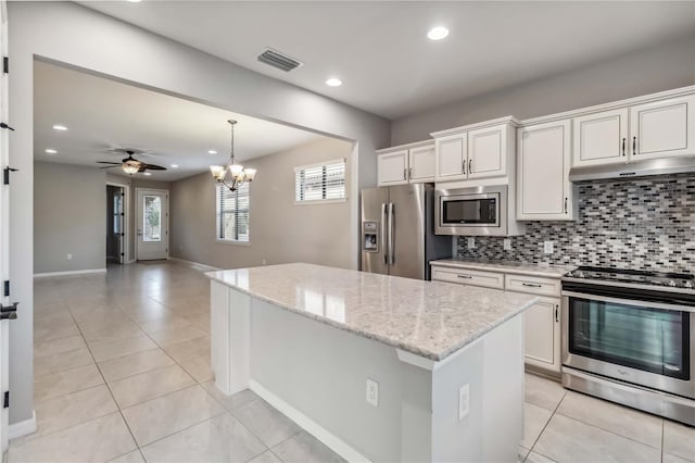 kitchen with tasteful backsplash, appliances with stainless steel finishes, white cabinets, and light stone counters