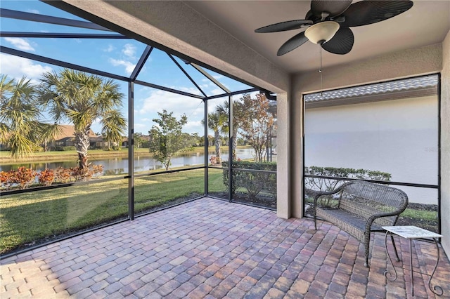 sunroom with ceiling fan and a water view