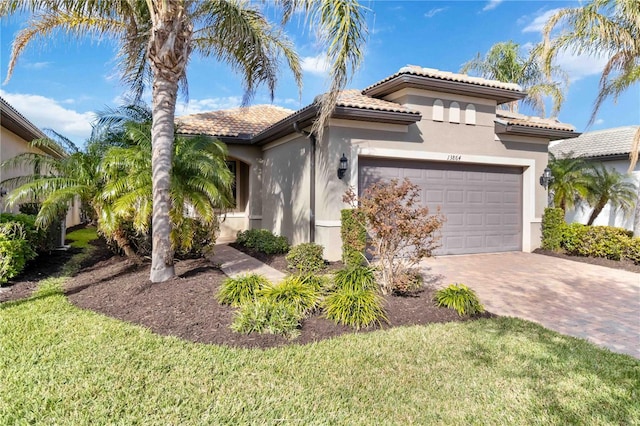 mediterranean / spanish home featuring a garage and a front lawn