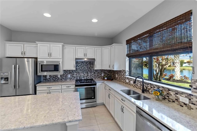 kitchen with sink, a water view, white cabinetry, appliances with stainless steel finishes, and backsplash