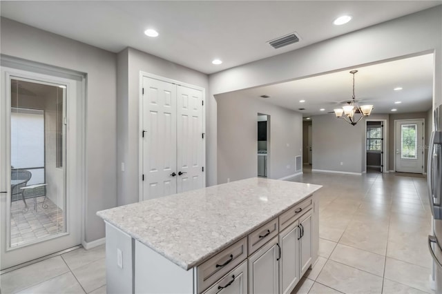 kitchen featuring a center island, light tile patterned floors, light stone counters, and decorative light fixtures