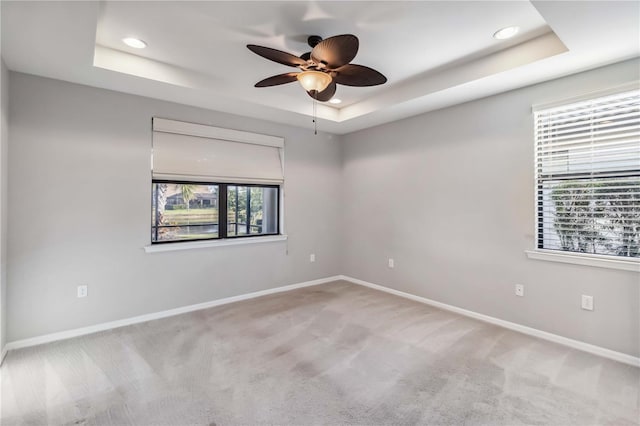 unfurnished room with a tray ceiling and light carpet